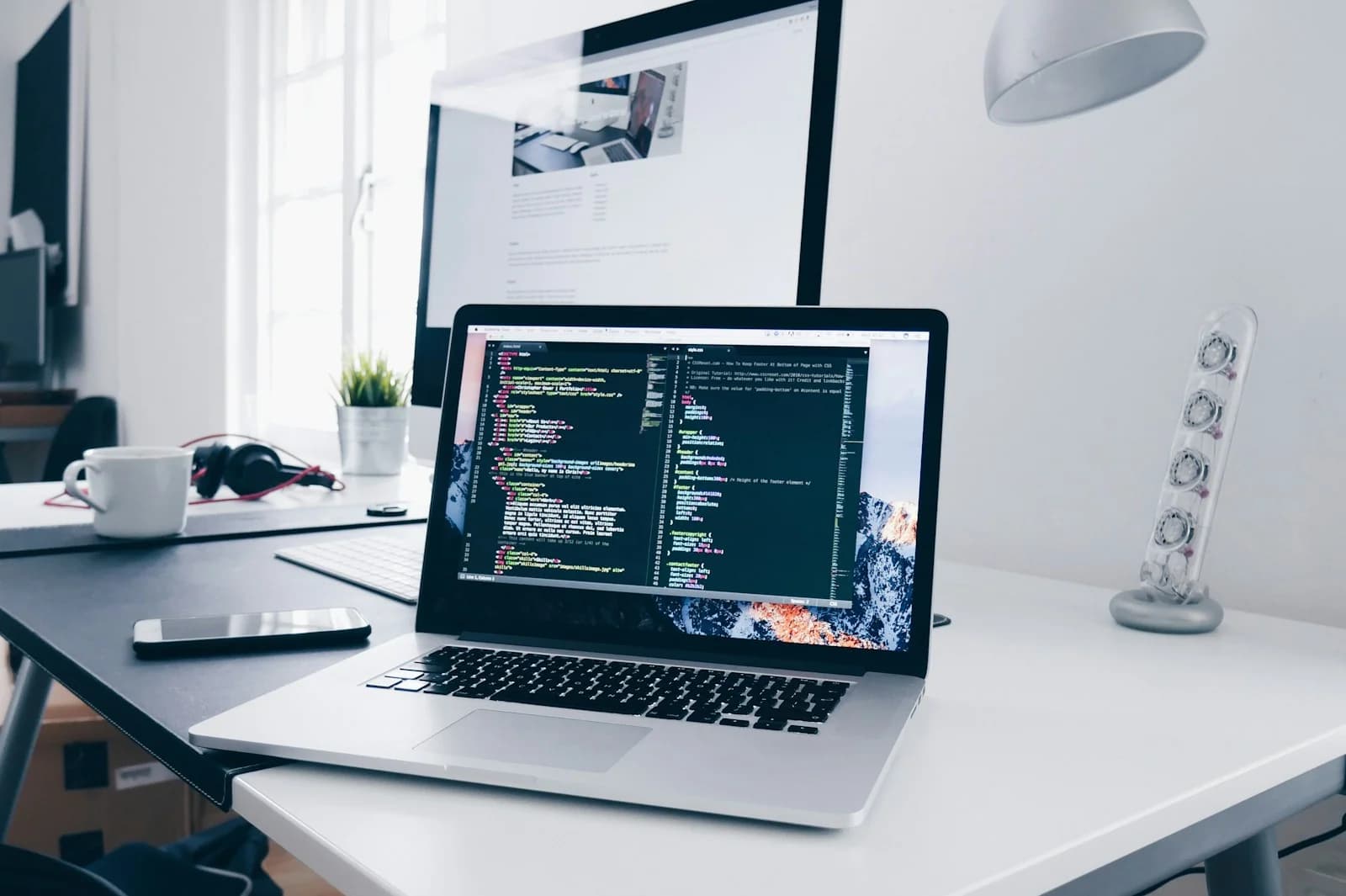 Laptop and desktop screen on a bright worktable; illustrative stock image